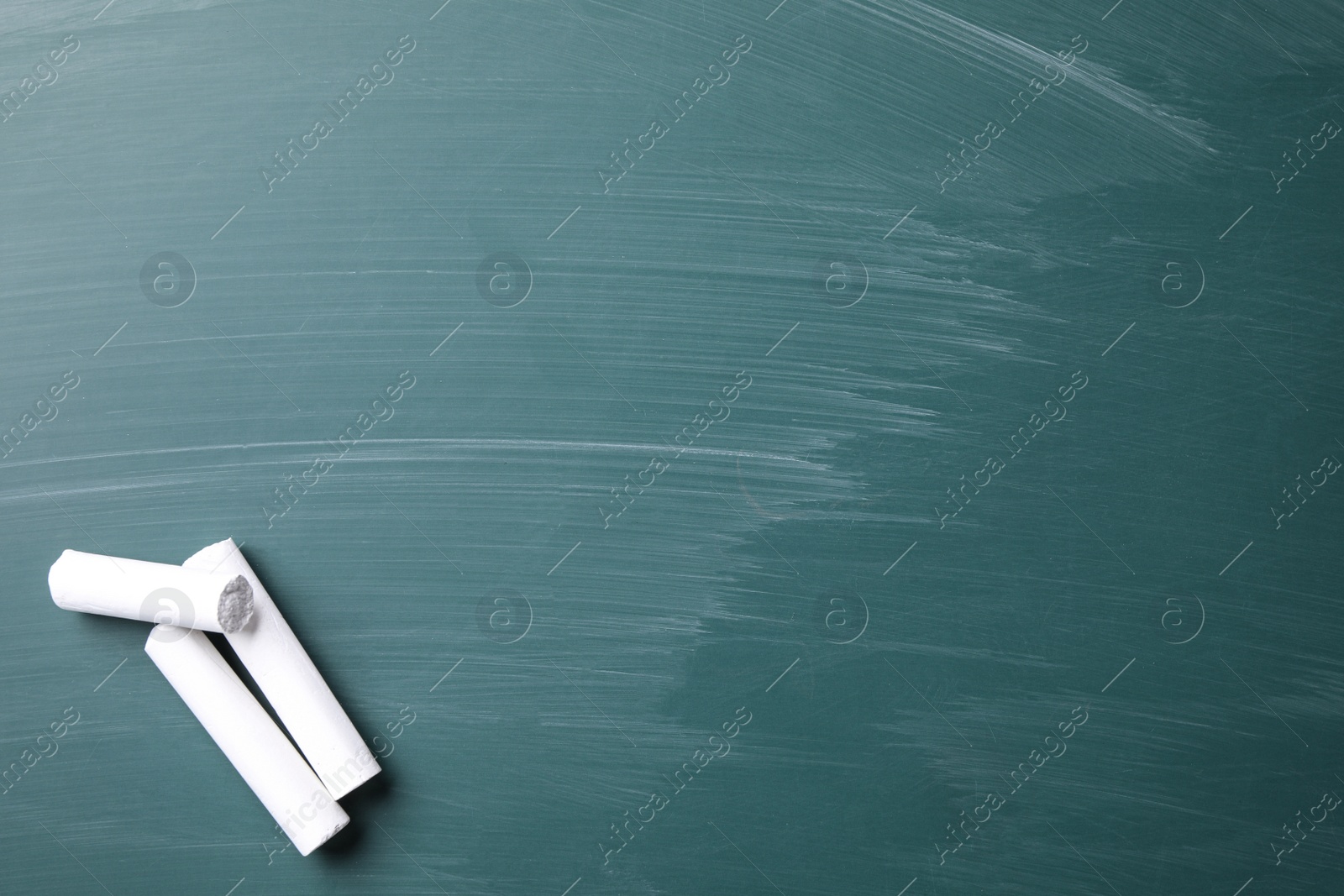 Photo of Pieces of white chalk on greenboard, flat lay. Space for text