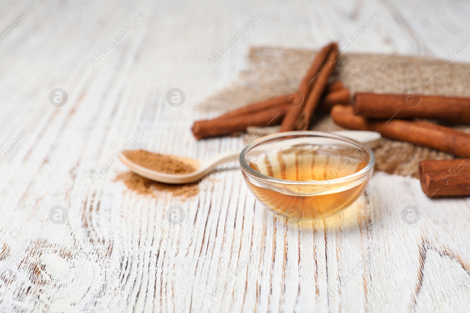 Photo of Little bowl with cinnamon essential oil on wooden table