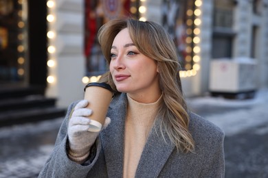 Photo of Portrait of charming woman with paper cup of coffee on city street in winter