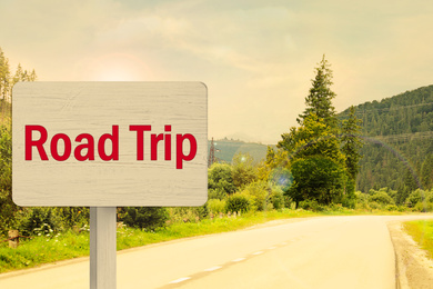 Image of Wooden plaque with inscription road trip on asphalt highway 