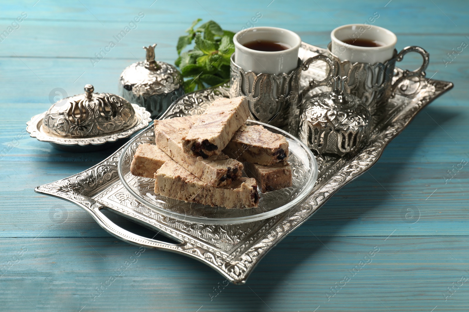 Photo of Tasty chocolate halva served on light blue wooden table