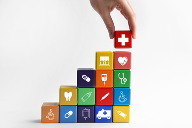 Woman building stairs with colorful cubes on white background. Health insurance concept