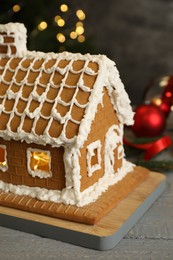 Beautiful gingerbread house decorated with icing on grey wooden table, closeup