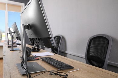 Open office interior. Modern workplaces with computers near light grey wall