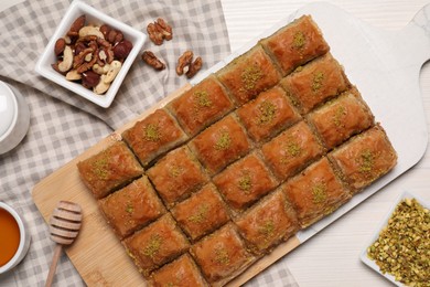 Photo of Delicious sweet baklava with ingredients on white wooden table, flat lay