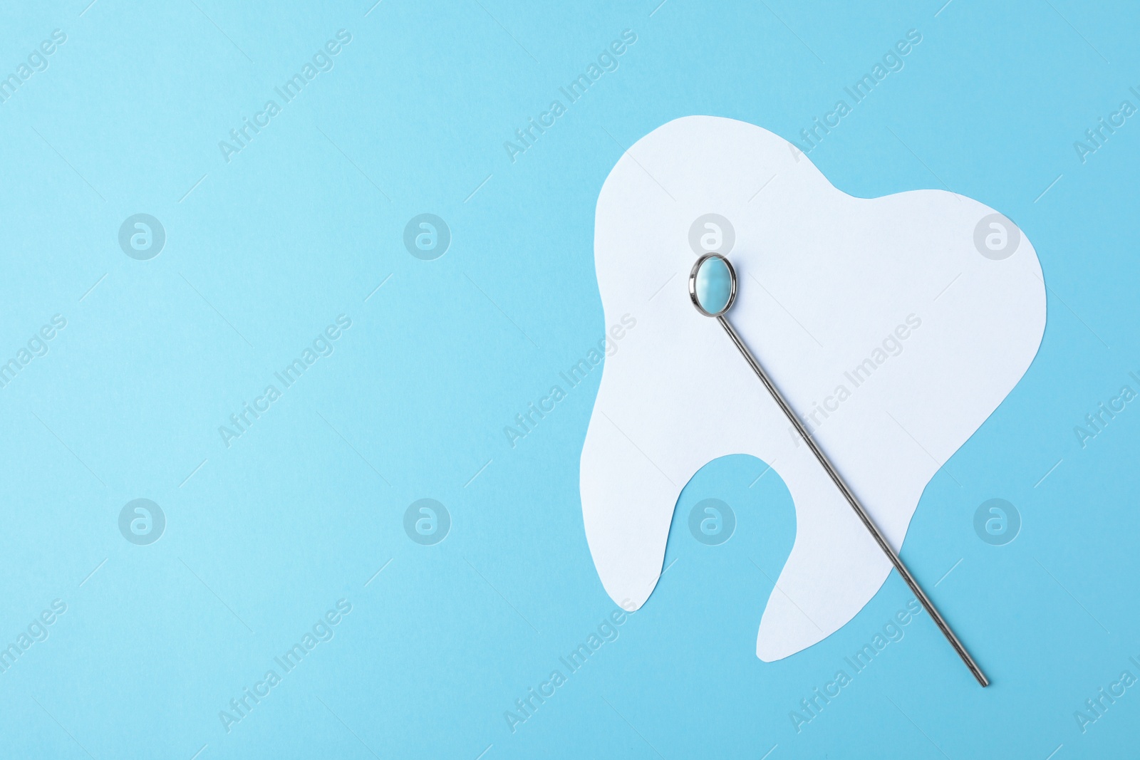 Photo of Paper tooth and dentist mirror on color background, top view with space for text