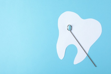 Paper tooth and dentist mirror on color background, top view with space for text