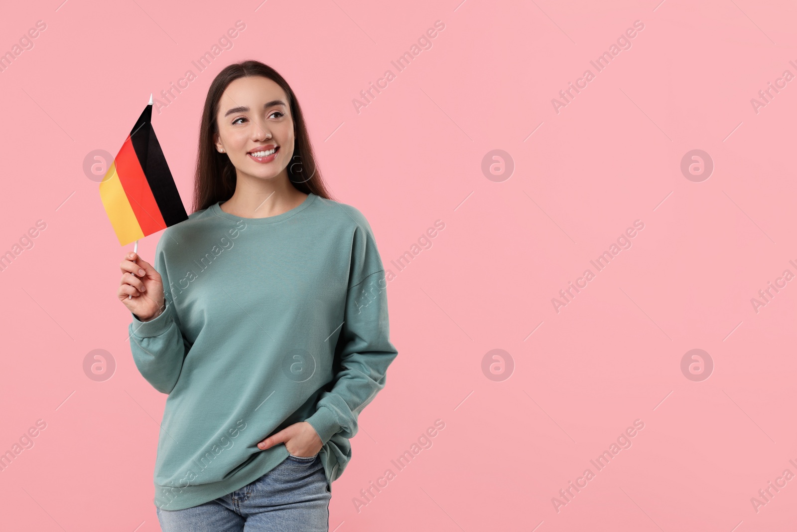 Photo of Young woman holding flag of Germany on pink background, space for text