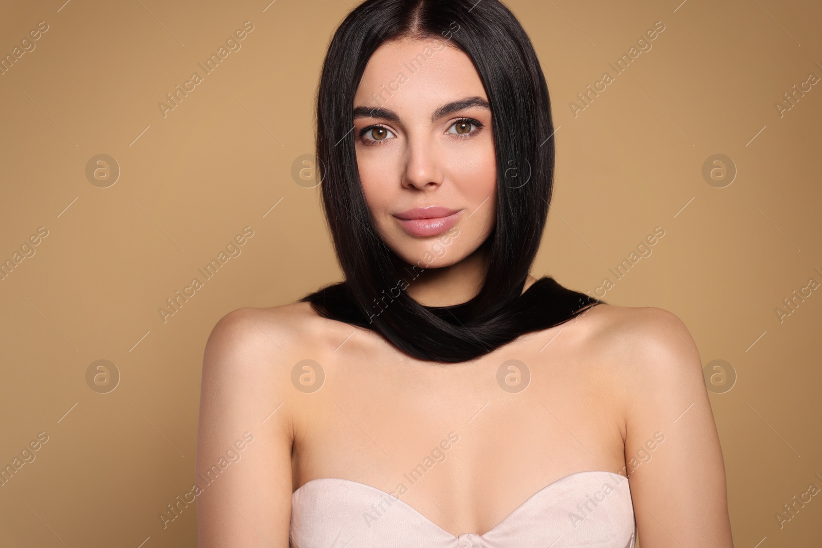 Photo of Portrait of beautiful young woman with healthy strong hair on beige background