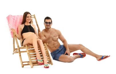 Young couple with sun lounger on white background. Beach accessories