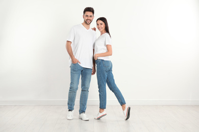 Photo of Young couple in stylish jeans near white wall