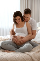 Young pregnant woman with her husband in bedroom