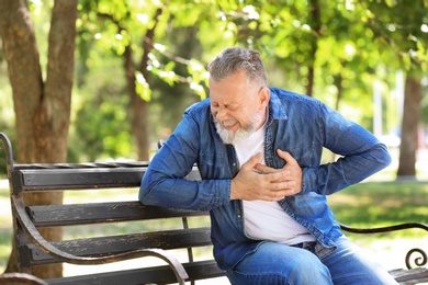 Photo of Mature man having heart attack on bench in park