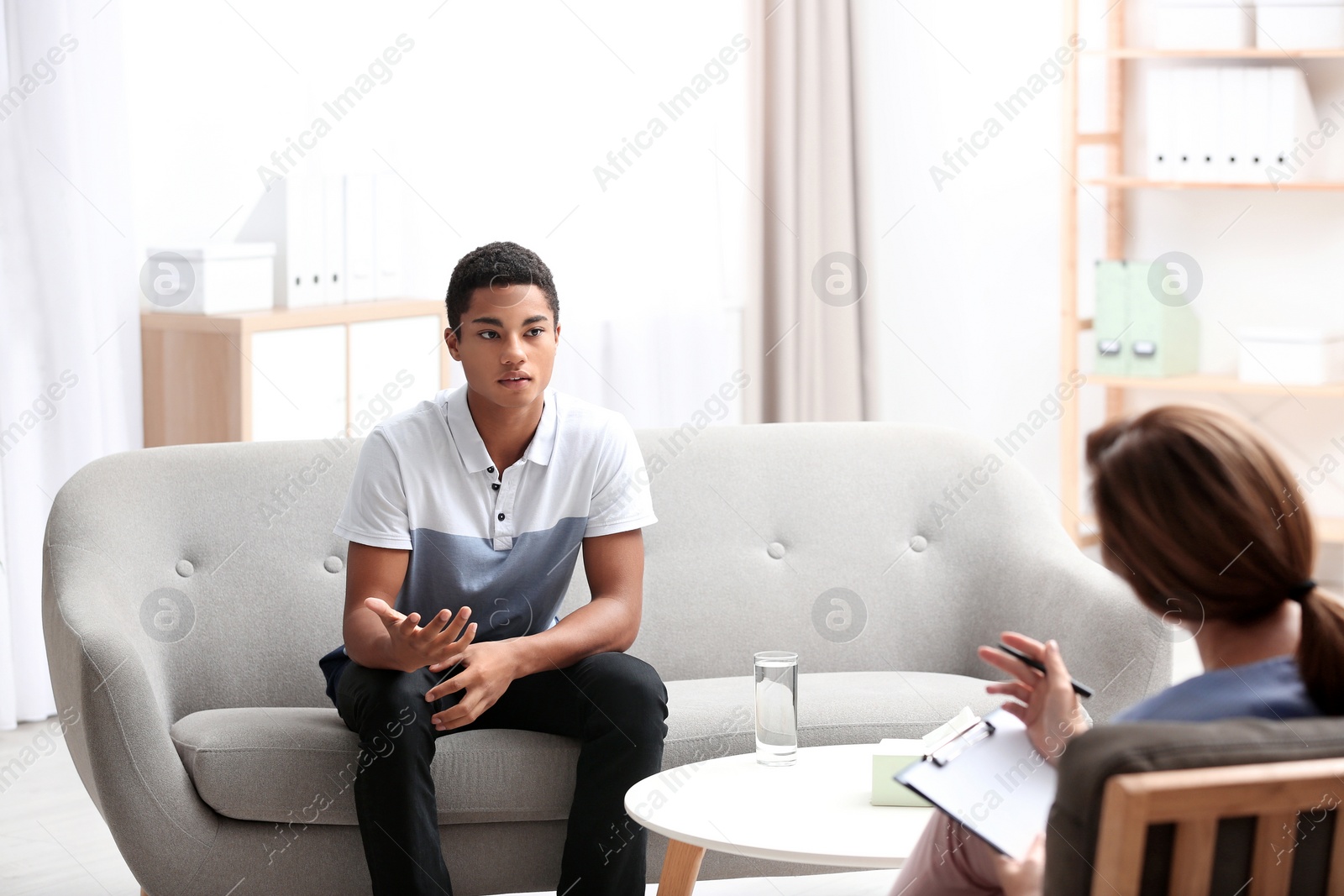 Photo of Psychotherapist working with African-American teenage boy in office