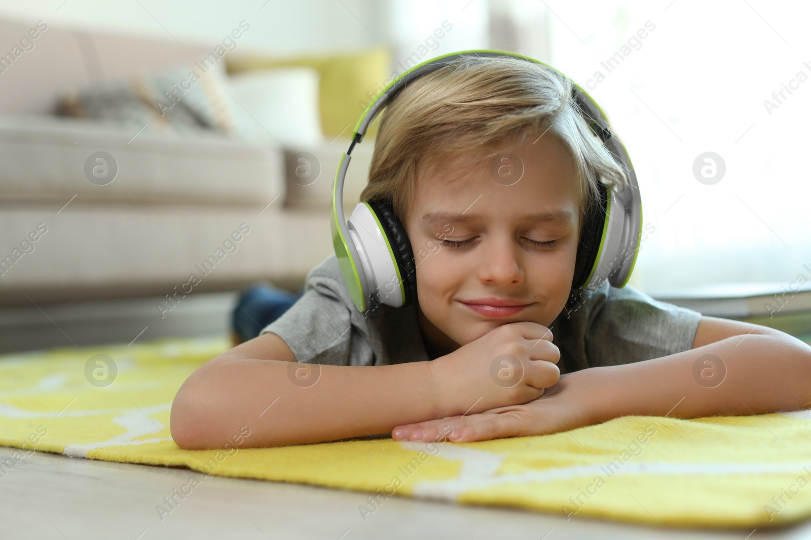 Photo of Cute little boy with headphones listening to audiobook at home