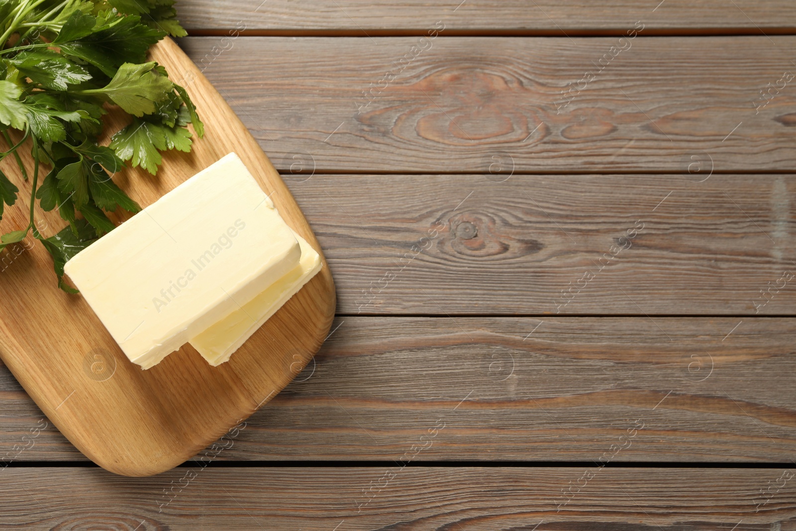 Photo of Tasty butter and parsley on wooden table, top view. Space for text