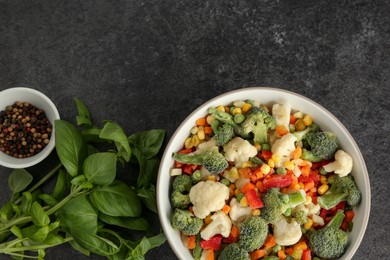Different frozen vegetables, spices and fresh basil on grey table, flat lay
