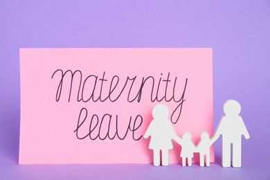 Photo of Card with phrase Maternity Leave and figures of family on violet background
