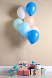 Photo of Many gift boxes and balloons near beige wall