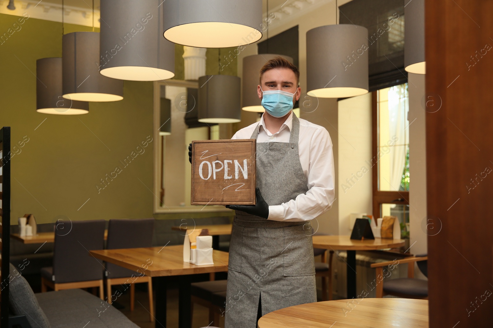 Photo of Waiter with OPEN sign in restaurant. Catering service during coronavirus quarantine