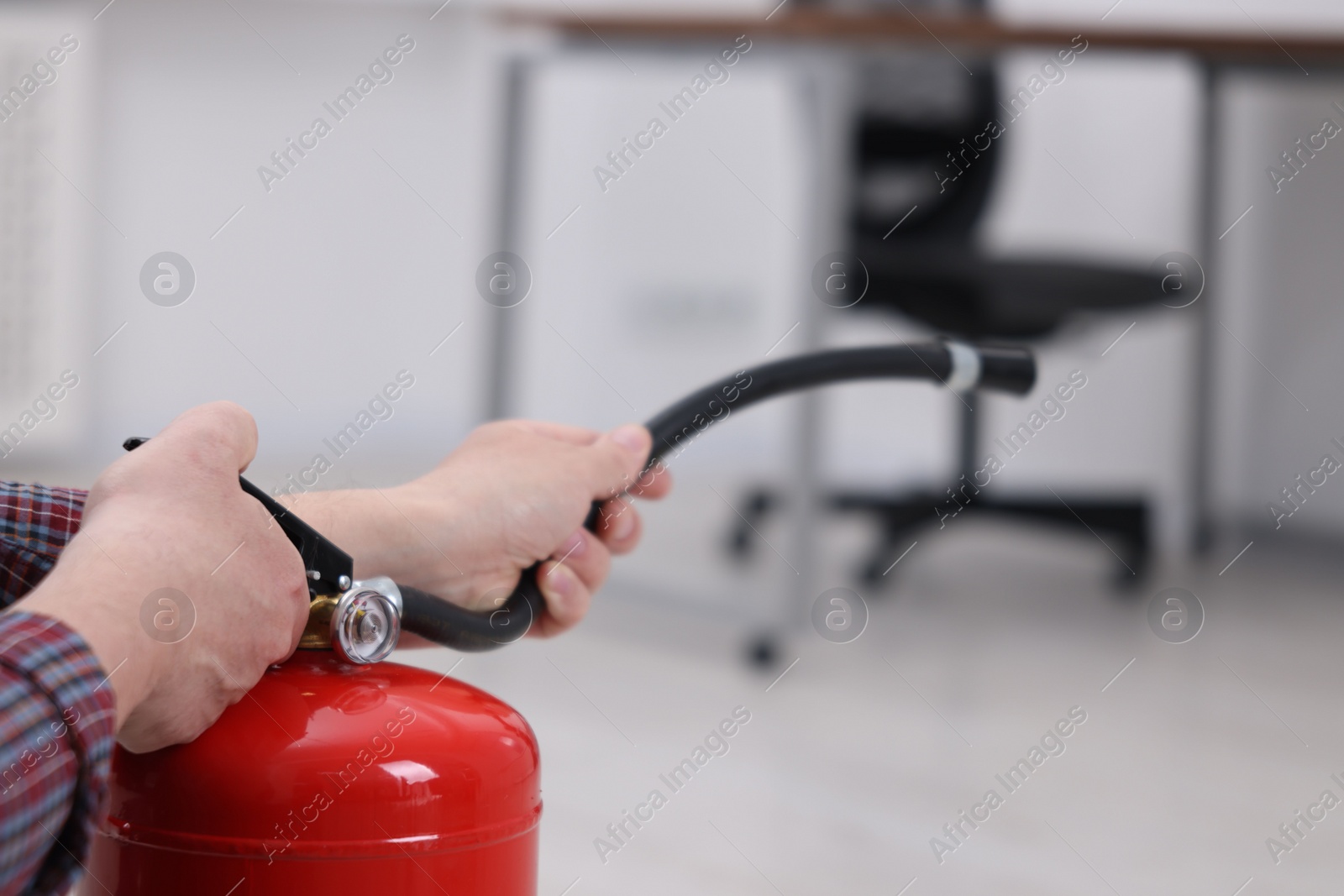 Photo of Man with one fire extinguisher indoors, closeup