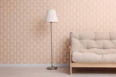 Image of Comfortable sofa and floor lamp near wall. Minimalist living room interior