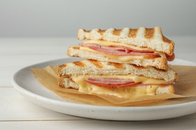 Photo of Tasty sandwiches with ham and melted cheese on white wooden table, closeup