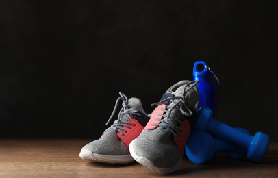 Photo of Gym equipment and accessories on floor against dark background. Space for text