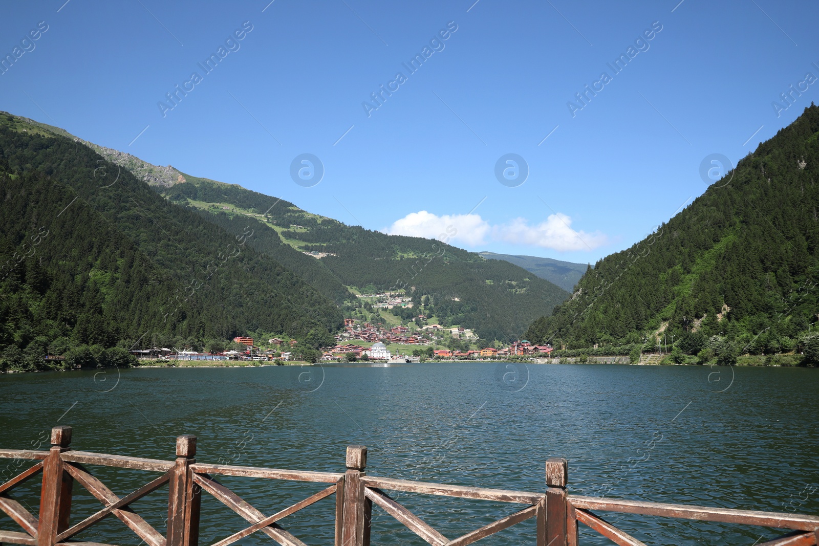 Photo of Buildings under mountains near lake on sunny day