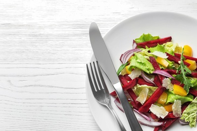 Plate with delicious beet salad on wooden background, top view