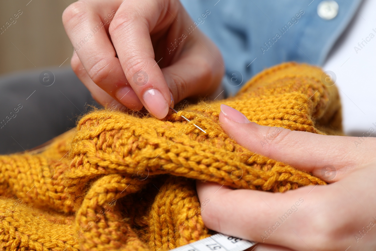 Photo of Woman sewing sweater with needle, closeup view