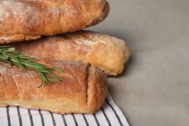 Fresh crispy baguettes on grey table, closeup. Space for text