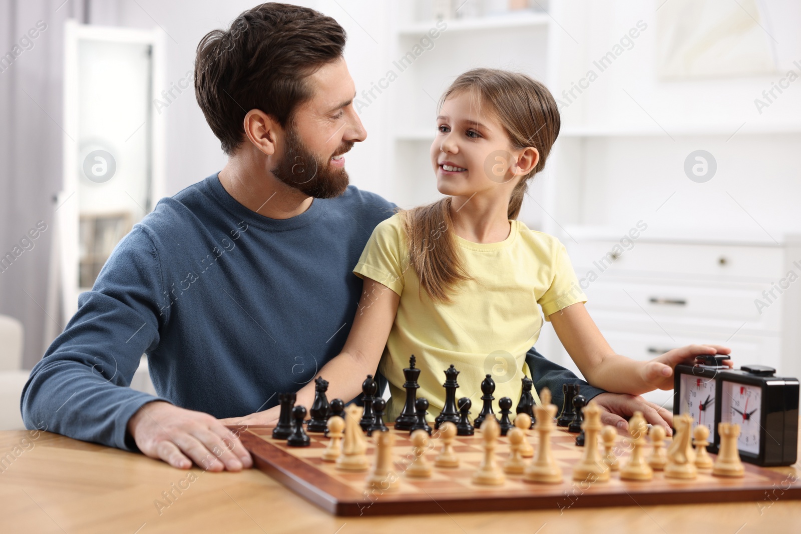 Photo of Father teaching his daughter to play chess at home