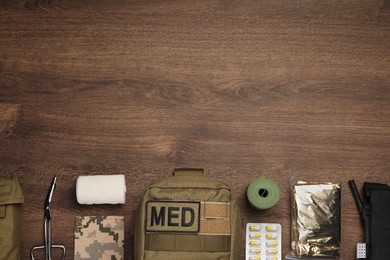 Military first aid kit on wooden table, flat lay. Space for text