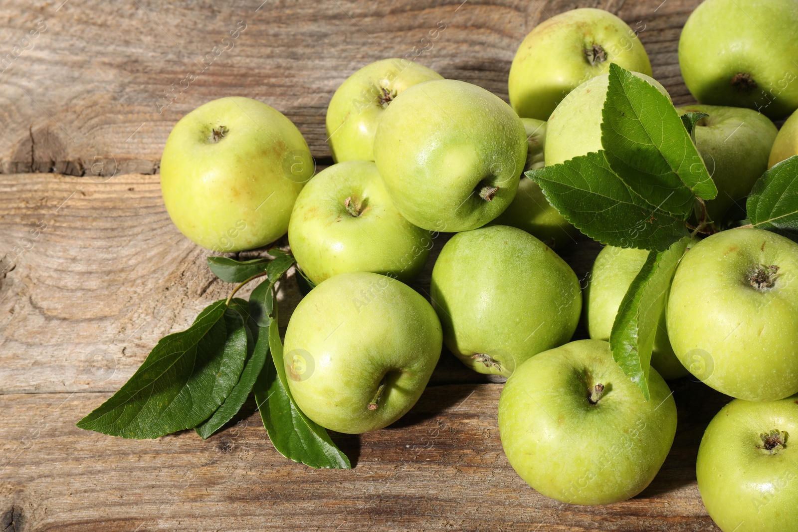 Photo of Many fresh apples and leaves on wooden table, above view