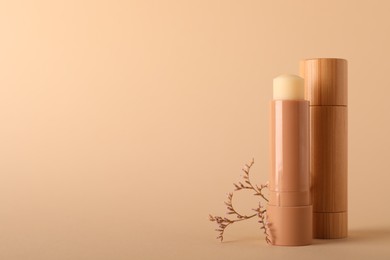 Photo of Lip balms on beige background, space for text