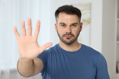 Handsome man showing stop gesture at home