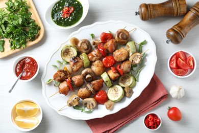 Photo of Delicious shish kebabs with vegetables and microgreens served on white table, flat lay