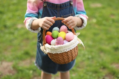 Photo of Easter celebration. Little girl holding basket with painted eggs outdoors, closeup