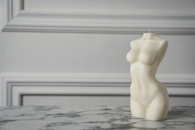 Photo of Stylish female body shaped candle on white marble table. Space for text