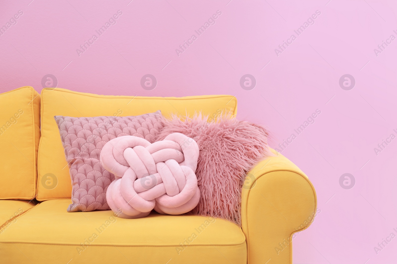 Photo of Sofa with different soft pillows on color background. Interior element