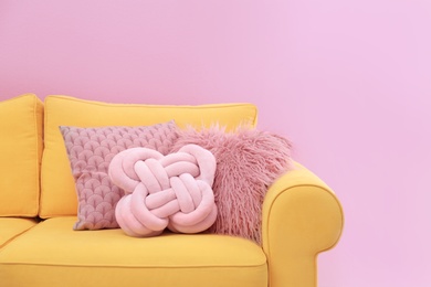 Sofa with different soft pillows on color background. Interior element