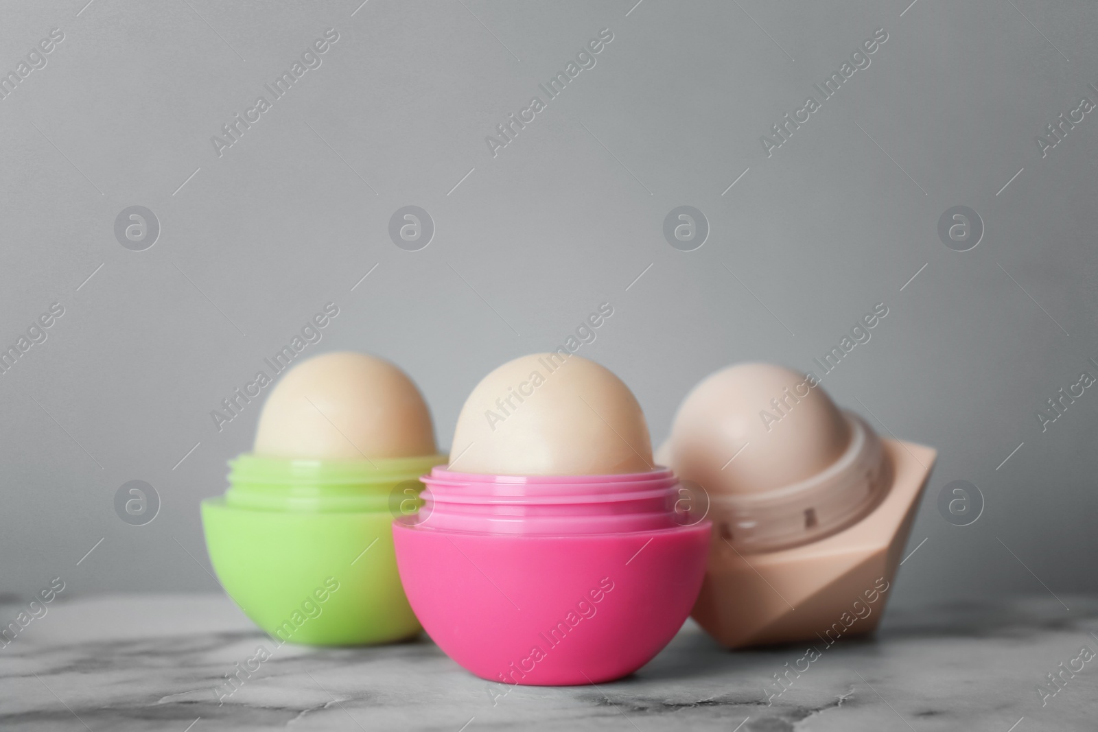 Photo of Lip balms on table against grey background