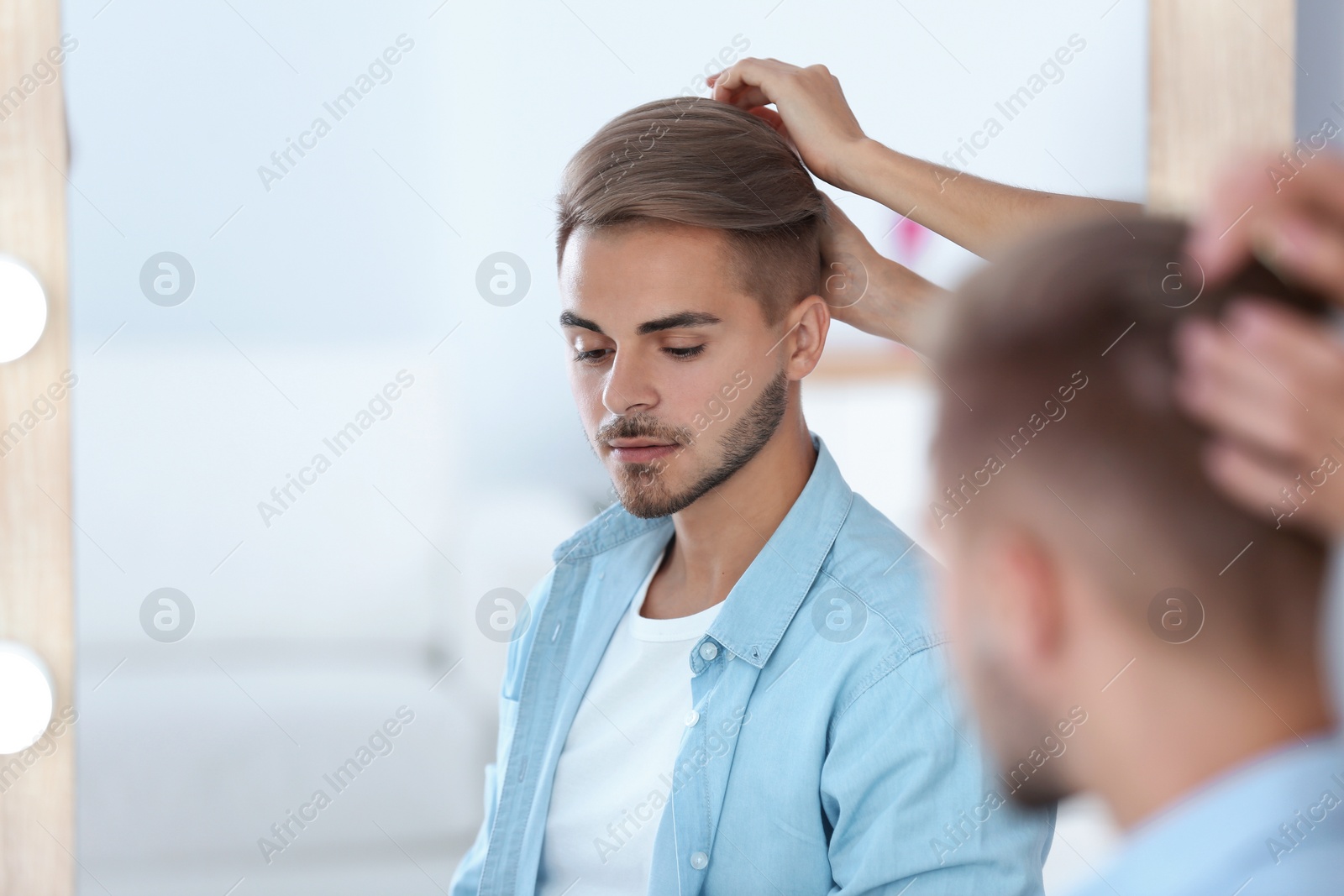 Photo of Professional hairdresser working with young man in barbershop. Trendy hair color