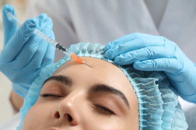 Photo of Doctor giving facial injection to young woman in clinic, closeup. Cosmetic surgery