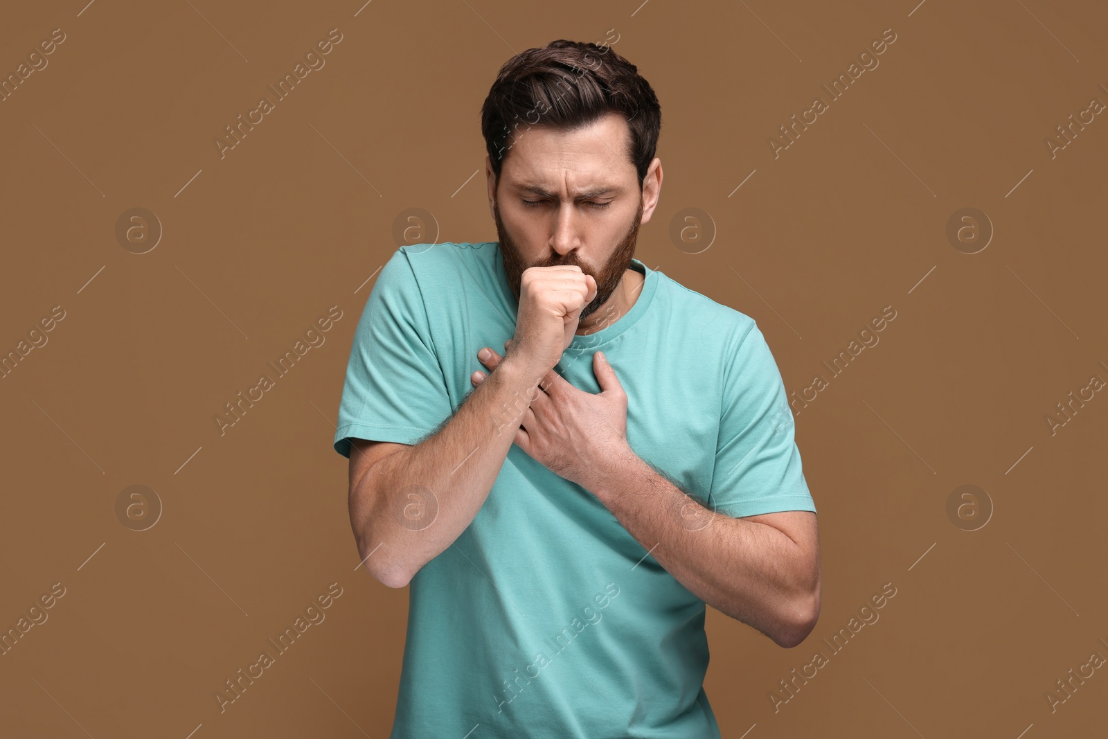 Photo of Sick man coughing on brown background. Cold symptoms