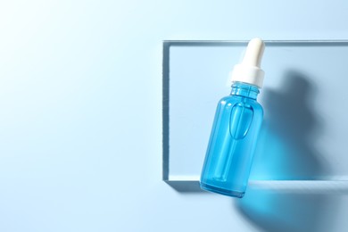 Photo of Bottle of cosmetic serum on light blue background, top view. Space for text