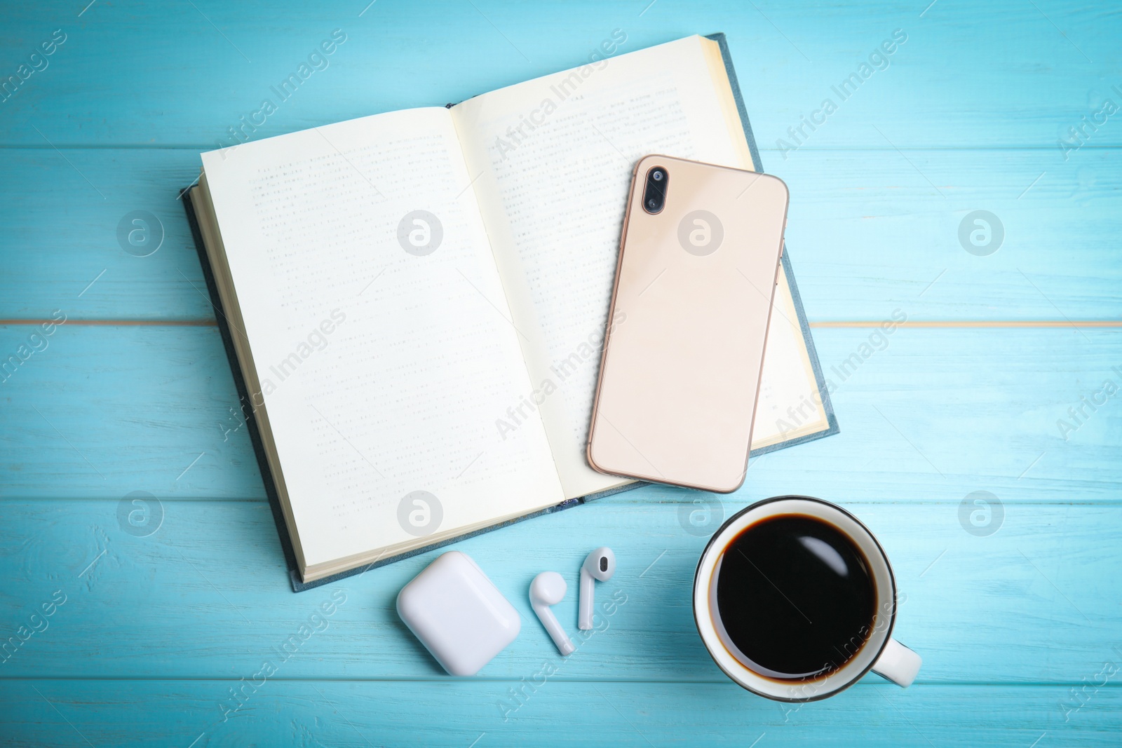 Photo of Book, coffee, earphones and mobile phone on light blue wooden table, flat lay