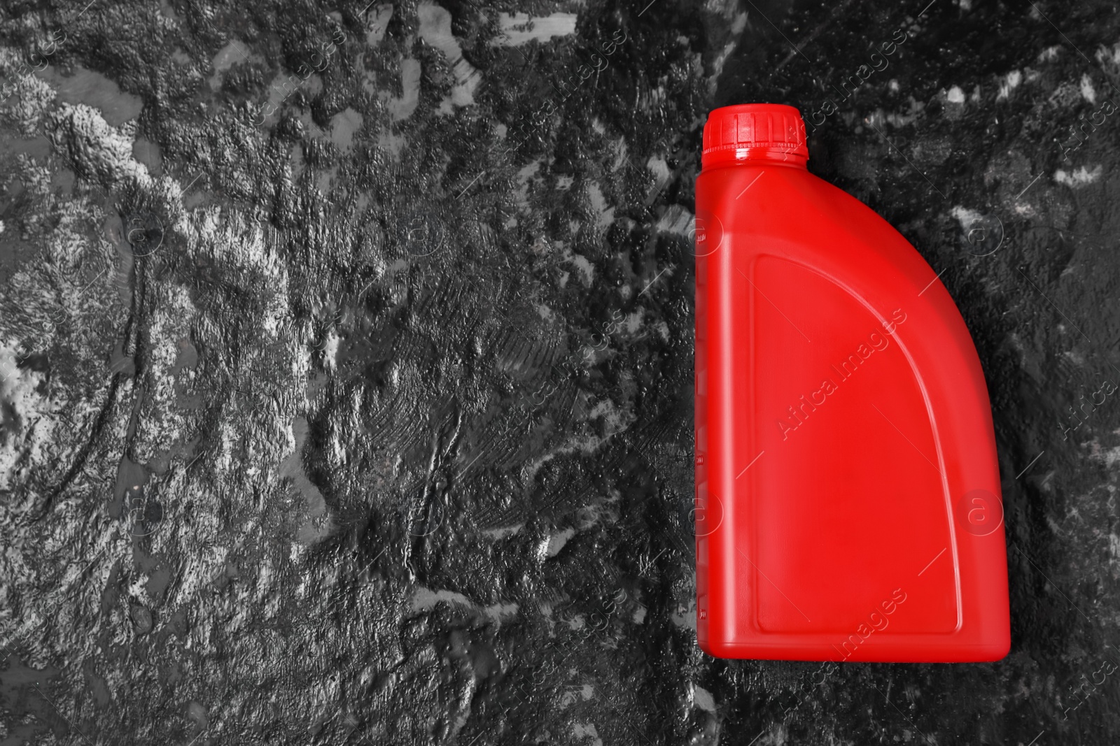 Photo of Motor oil in red canister on black table, top view. Space for text