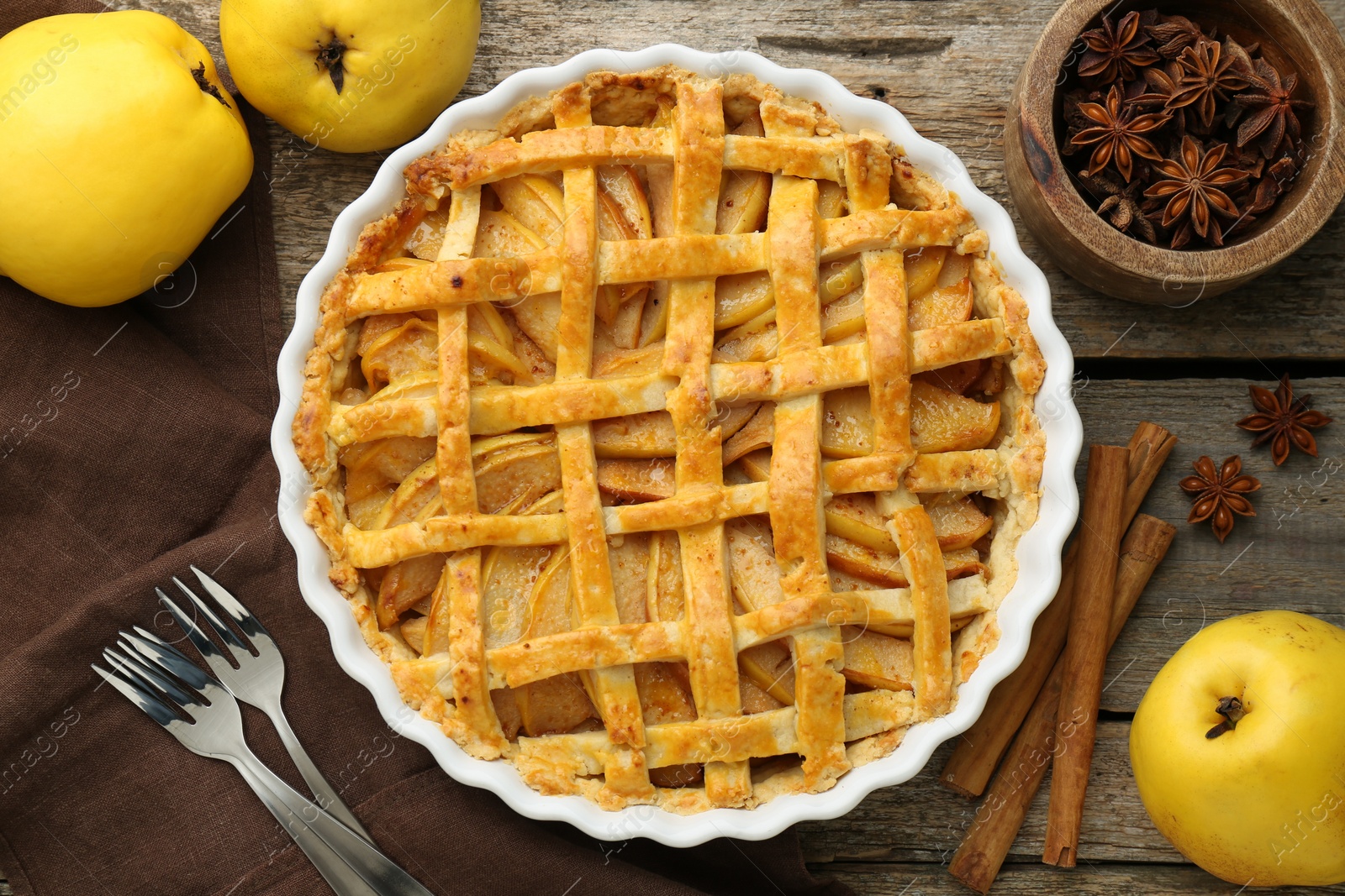 Photo of Tasty homemade quince pie served on wooden table, flat lay